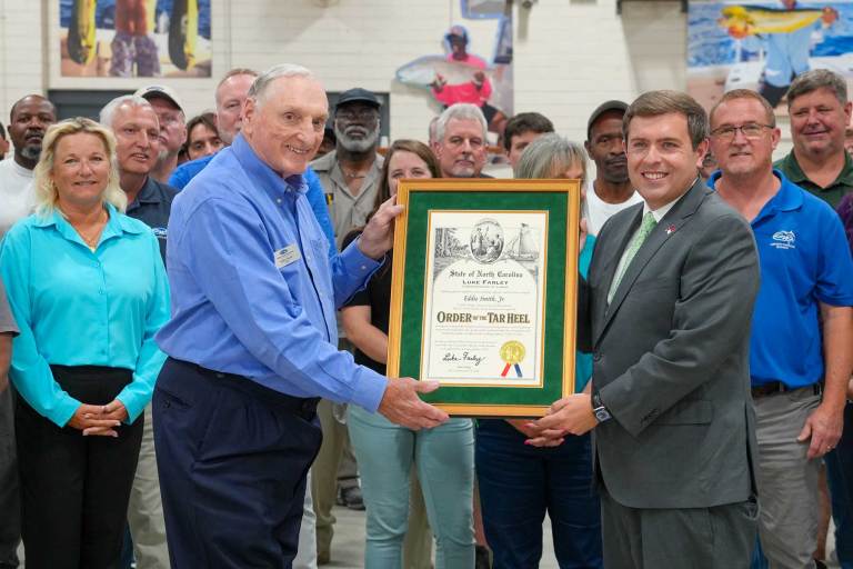 1_GRADY.WHITE-260611 The focus on two men with an awards frame being held by both of them surrounded by on lookers