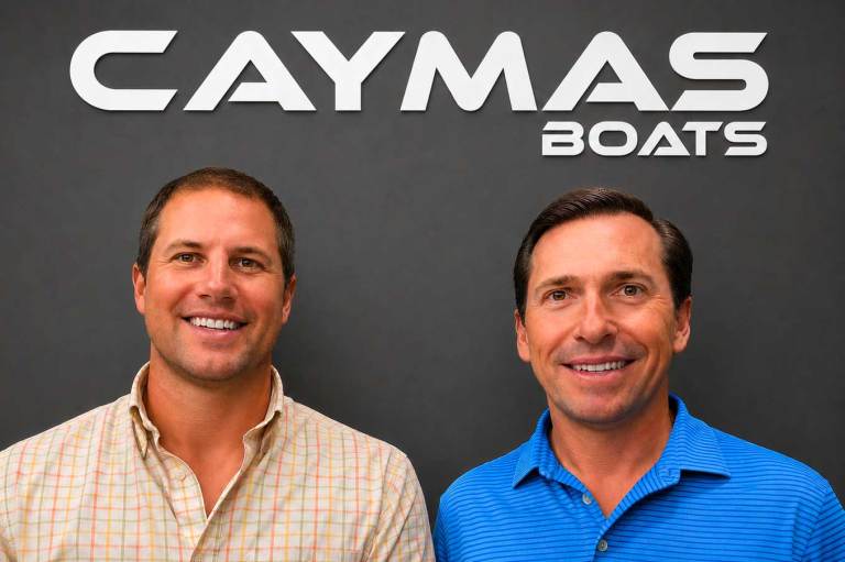 1_CAYMAS-260720 To men mugging in front of a Caymas Boat Sign