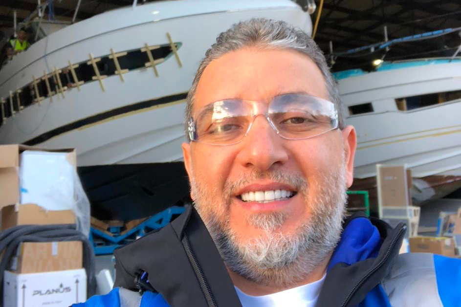 Close up photo of a man's face, he has a boat behind him.