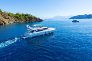 An expensive looking motor yacht cruising off the coastline on an exotic location with mountains in the distance