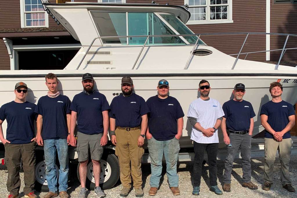 Bunch of guys standing in front of a large boat.