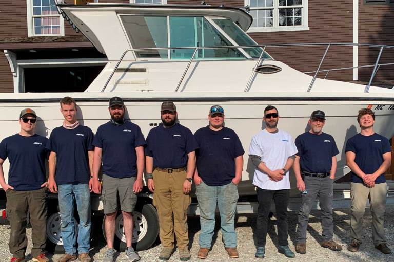 Bunch of guys standing in front of a large boat.