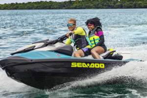 Two young people rideing on a jet ski in the water.