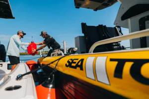 yellow boat close up. man handing over a small red gas can.